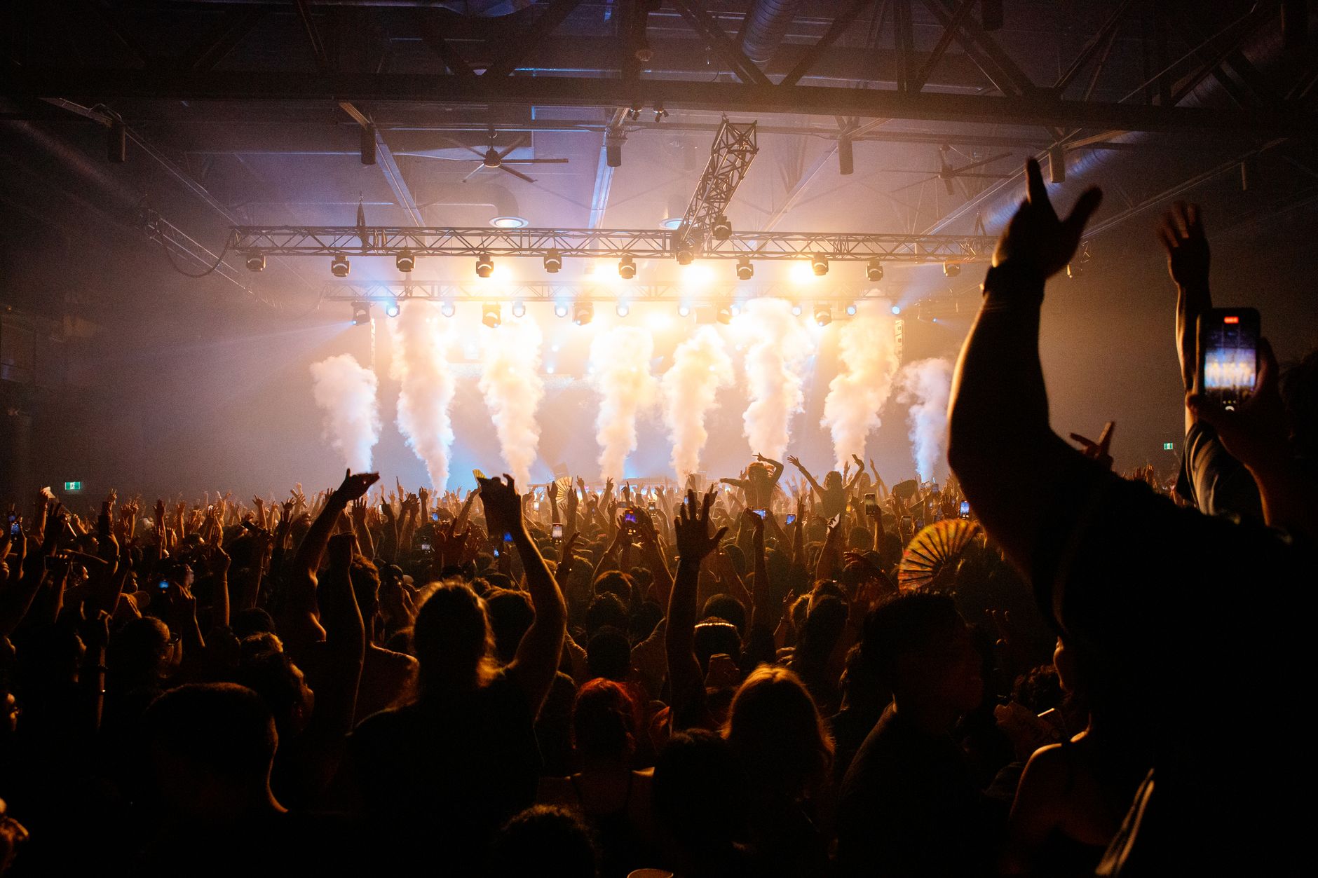 Packed crowd under stage lights and haze